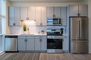 a kitchen with gray cabinets and a black and white rug
